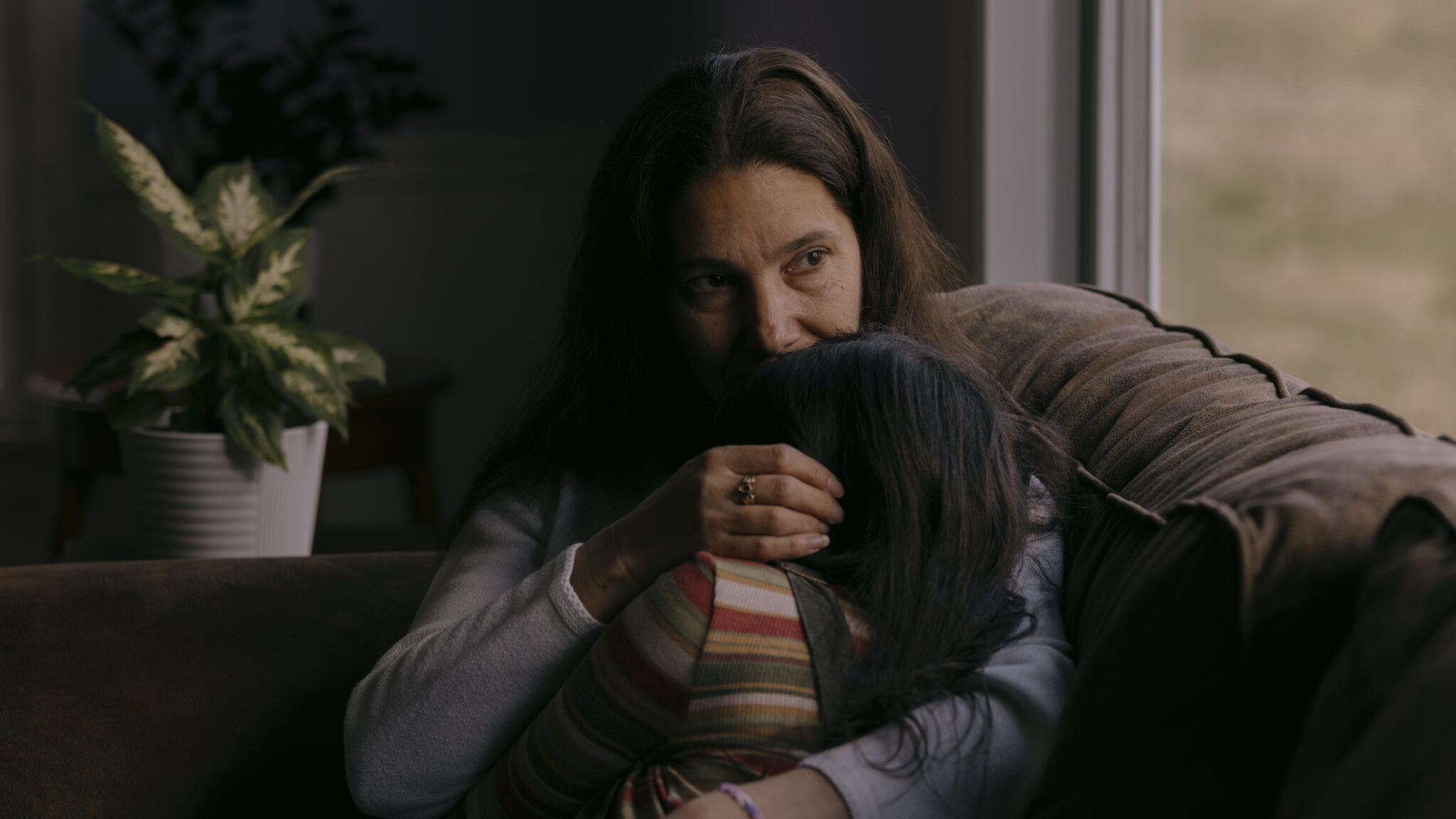 Tara Skopelitis hugs her daughter Andi while sitting on a couch