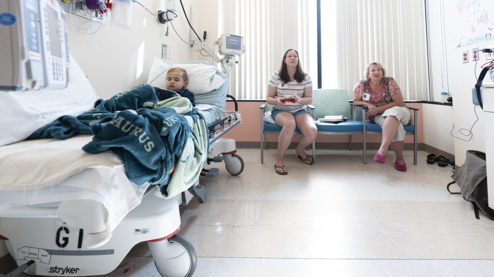 Hiram Secrist sits in a hospital bed beside his mother, Kristen Secrist, and his grandmother, Terrie Jordan.