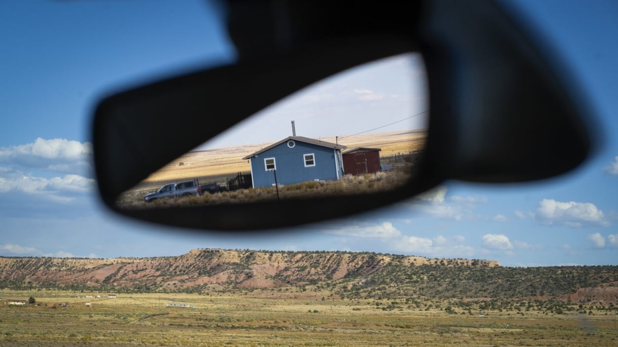 A house is reflected in a car's rearview mirror on the Navajo Nation near Window Rock, Ariz.