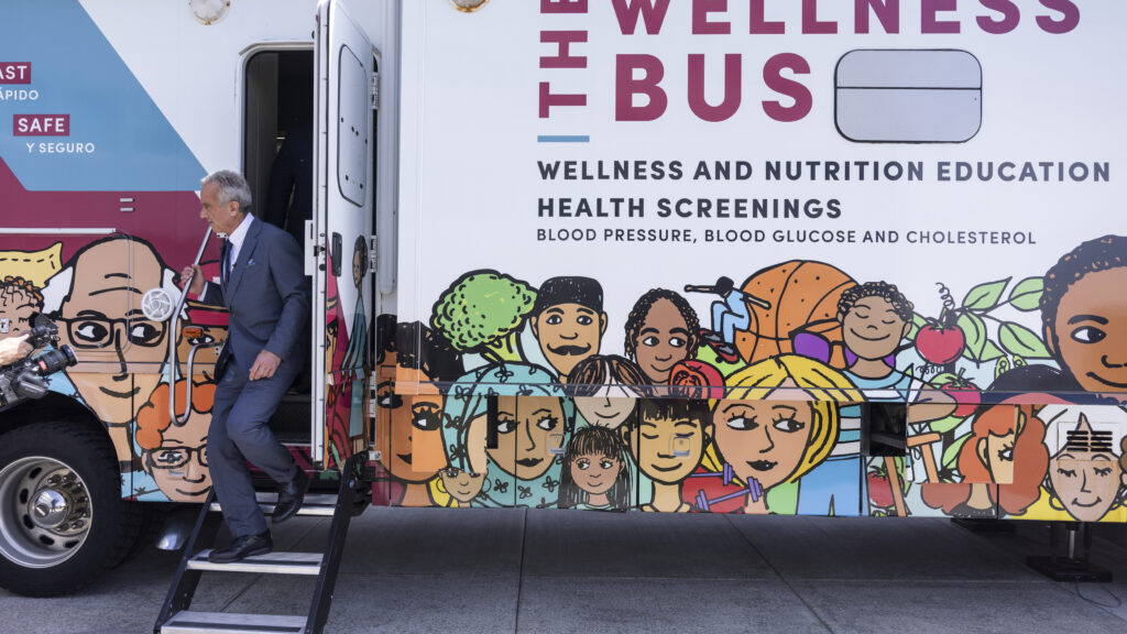 RFK Jr. steps off a bus that advertises wellness and nutrition education health screenings