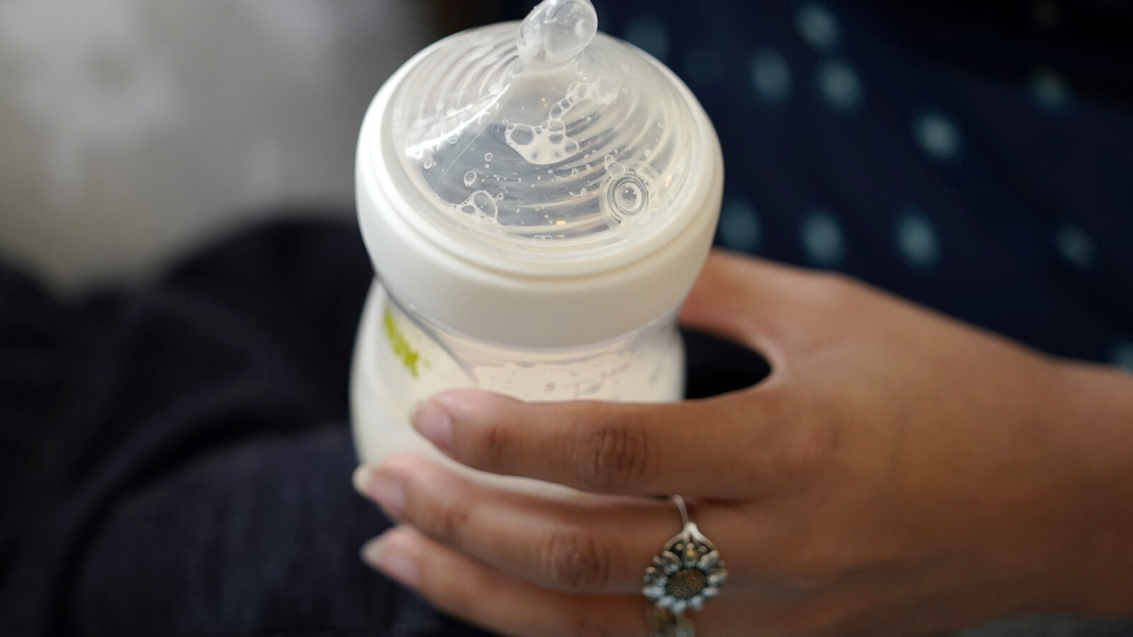 a close-up of a hand holding a baby bottle with milk inside