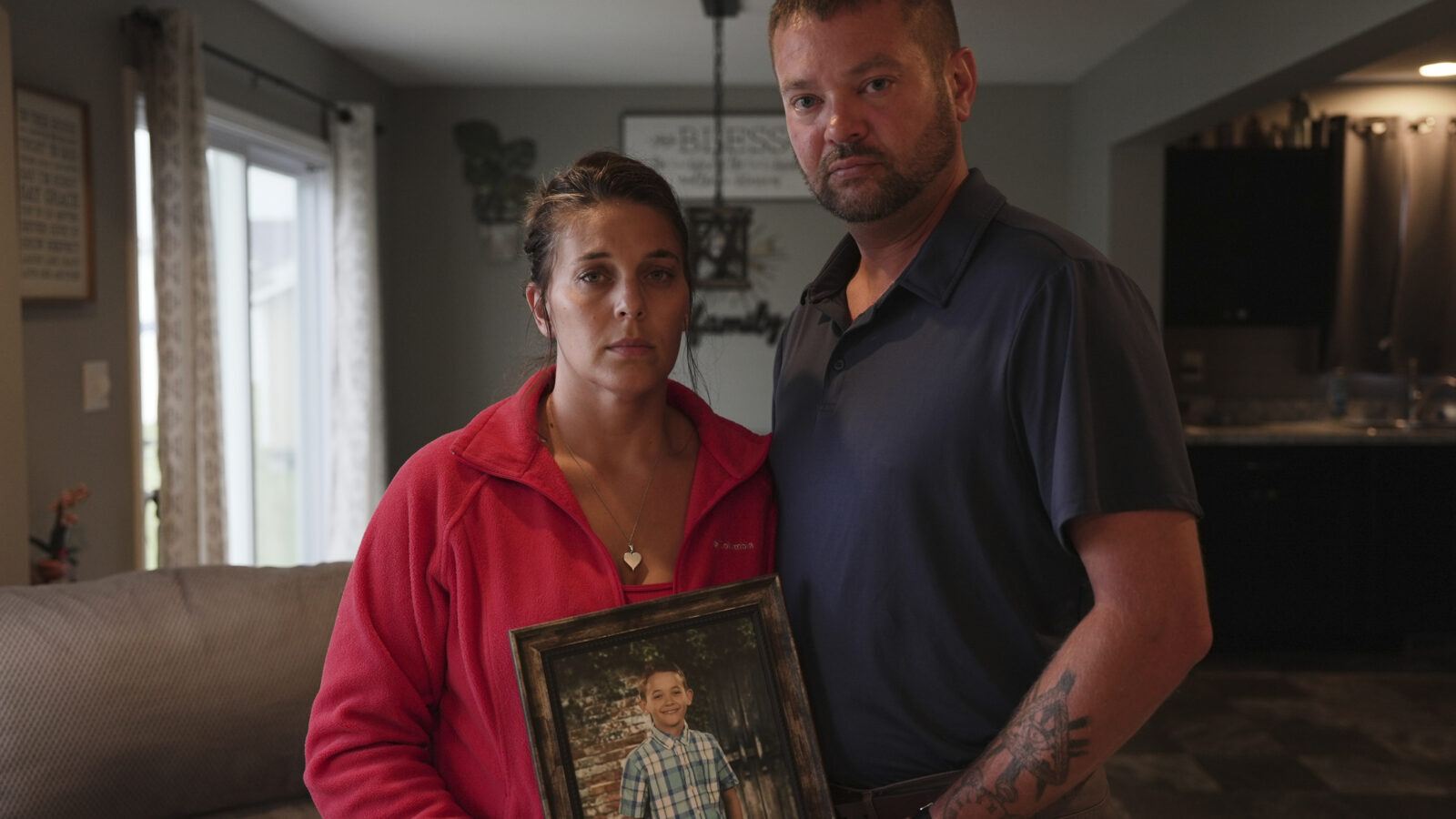 Two parents hold a framed photo of their son, who died from a vaccine preventable disease.