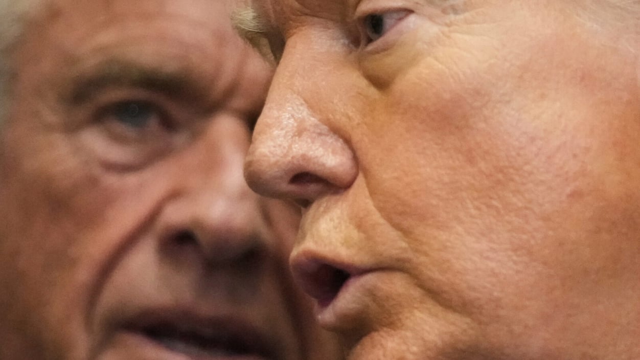 An extreme close up of Trump's face as he speaks, with Kennedyt's face close behind him, watching