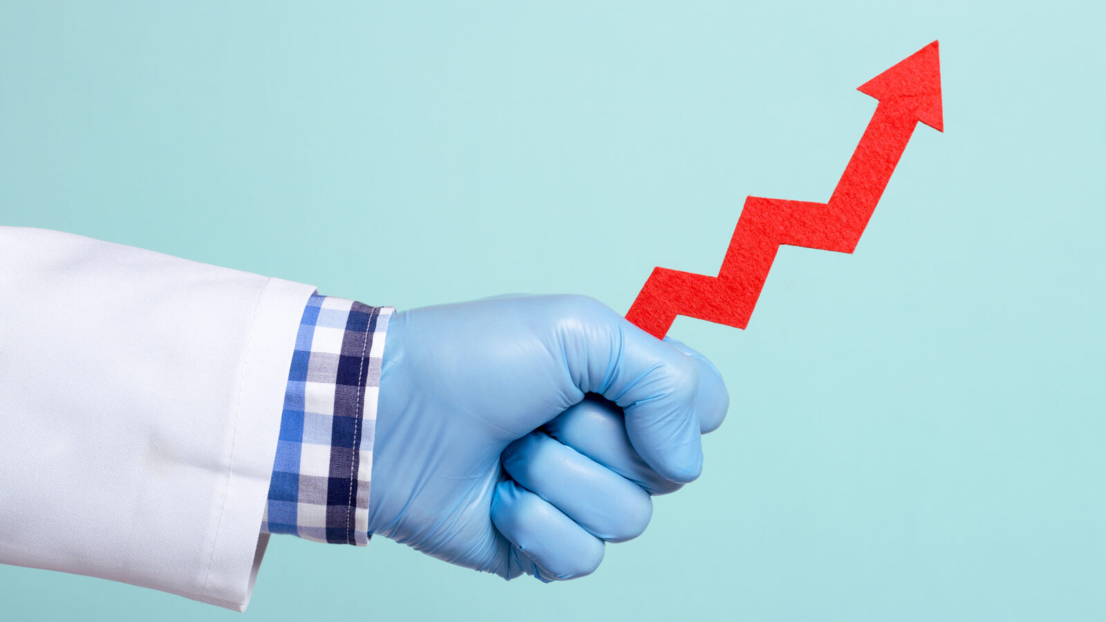 Close-up of a hand with a blue surgical glove holding a red arrow pointing upward