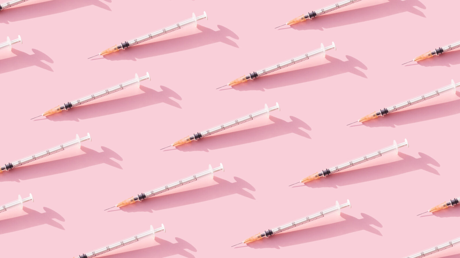 A stock image of needles lined up in rows against a pink background