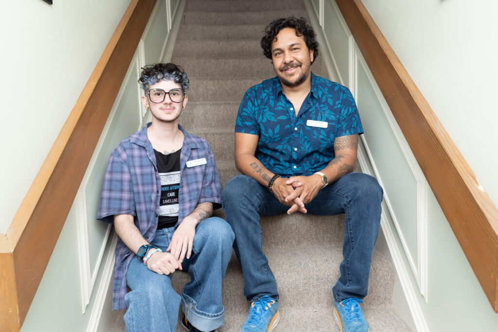 Indigo and Michael sit on the carpeted stairs inside the Savannah Pride Center.