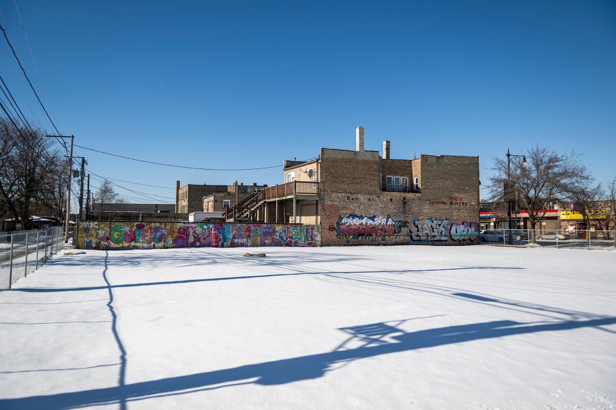 A plot of land covered in snow next to a building.