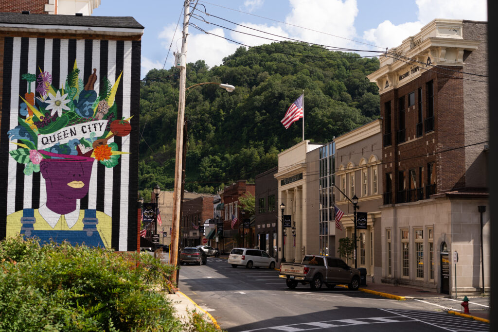 A scene of downtown Hazard, Ky. that shows a painted mural of flowers coming out of a woman's head, with the text "Queen City."