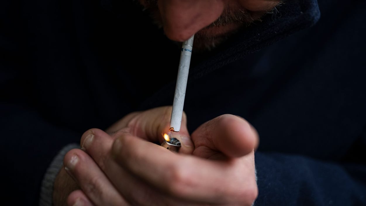 a hand lights a cigarette against a black background