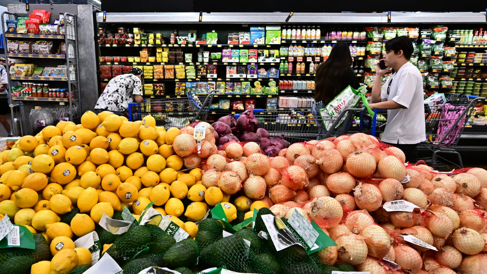Oranges and onions sit in a huge pile in the grocery store.