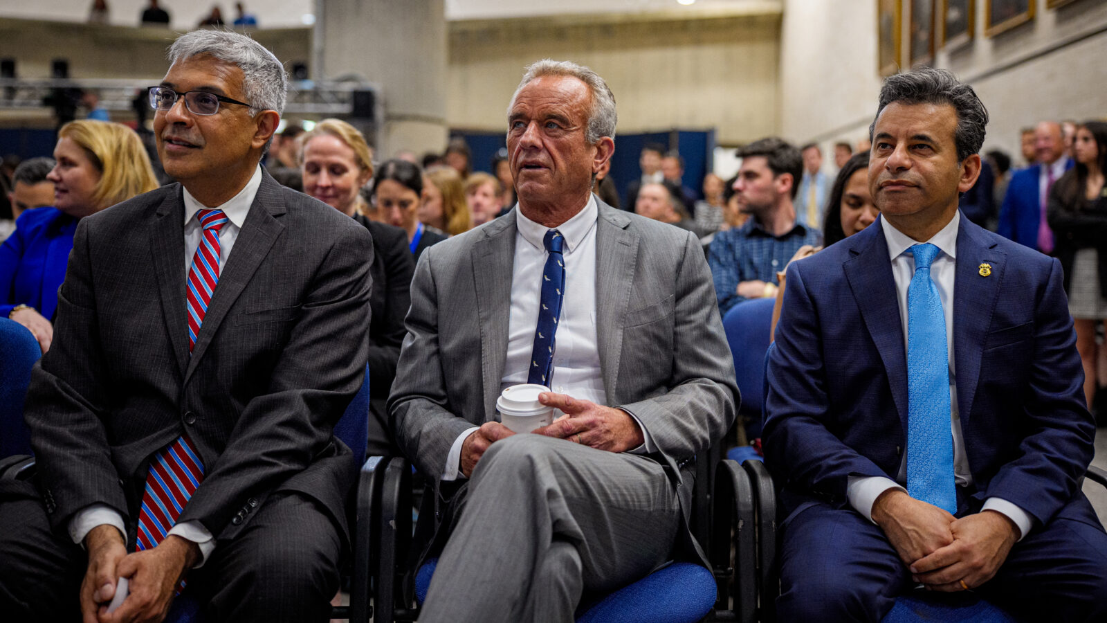 Jay Battacharya, Robert F. Kennedy, and Marty Makary sit in chairs at an event.