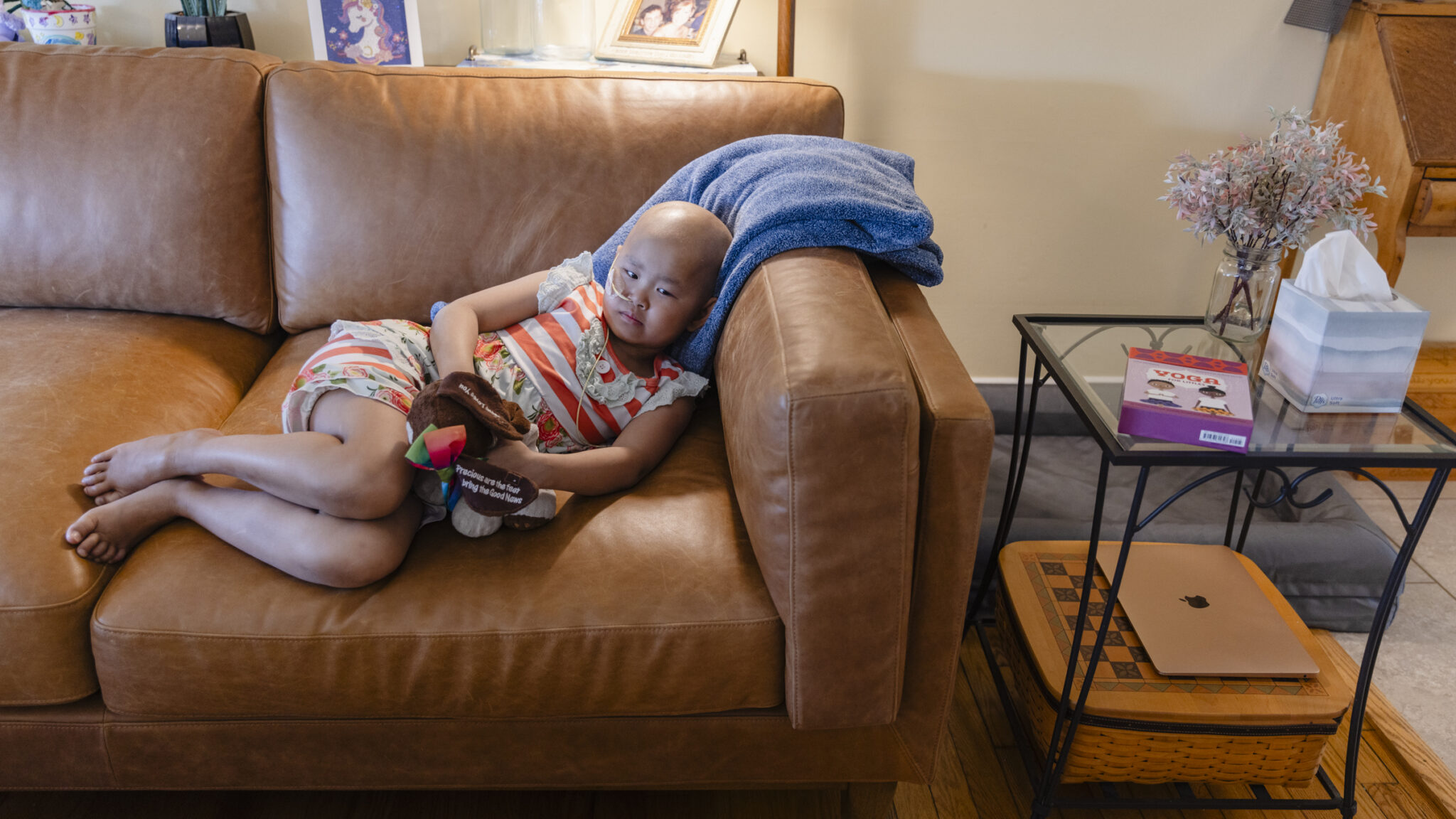 7-year-old Shelby Campbell holds a stuffed animal while resting on a brown leather couch.