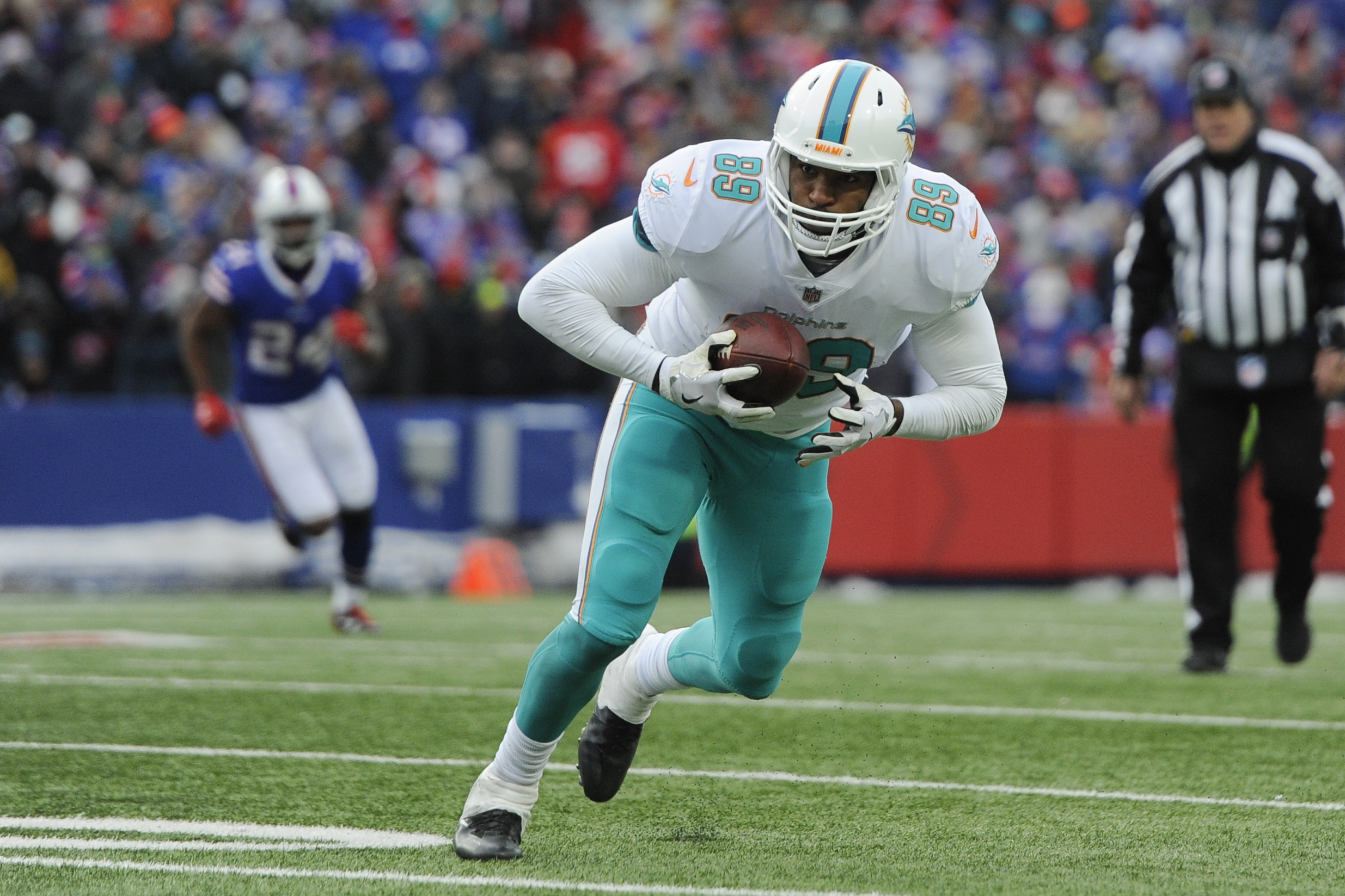 Former Miami Dolphins player Julius Thomas holds a football as he runs on field