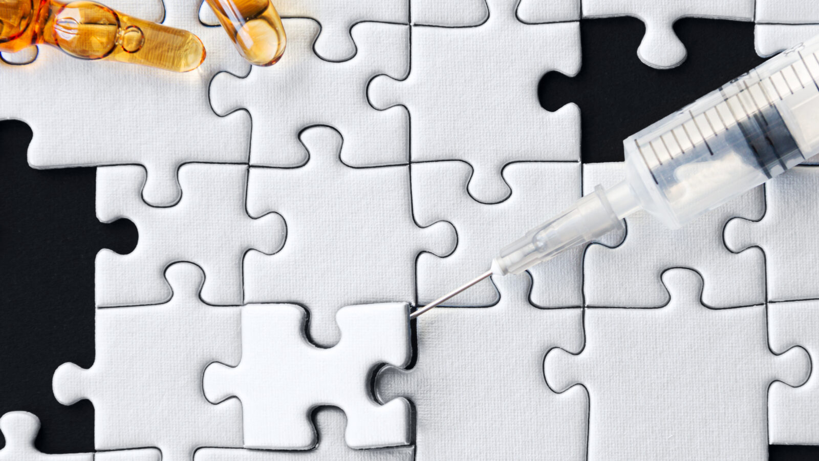 A syringe pokes to remove a piece up from a puzzle