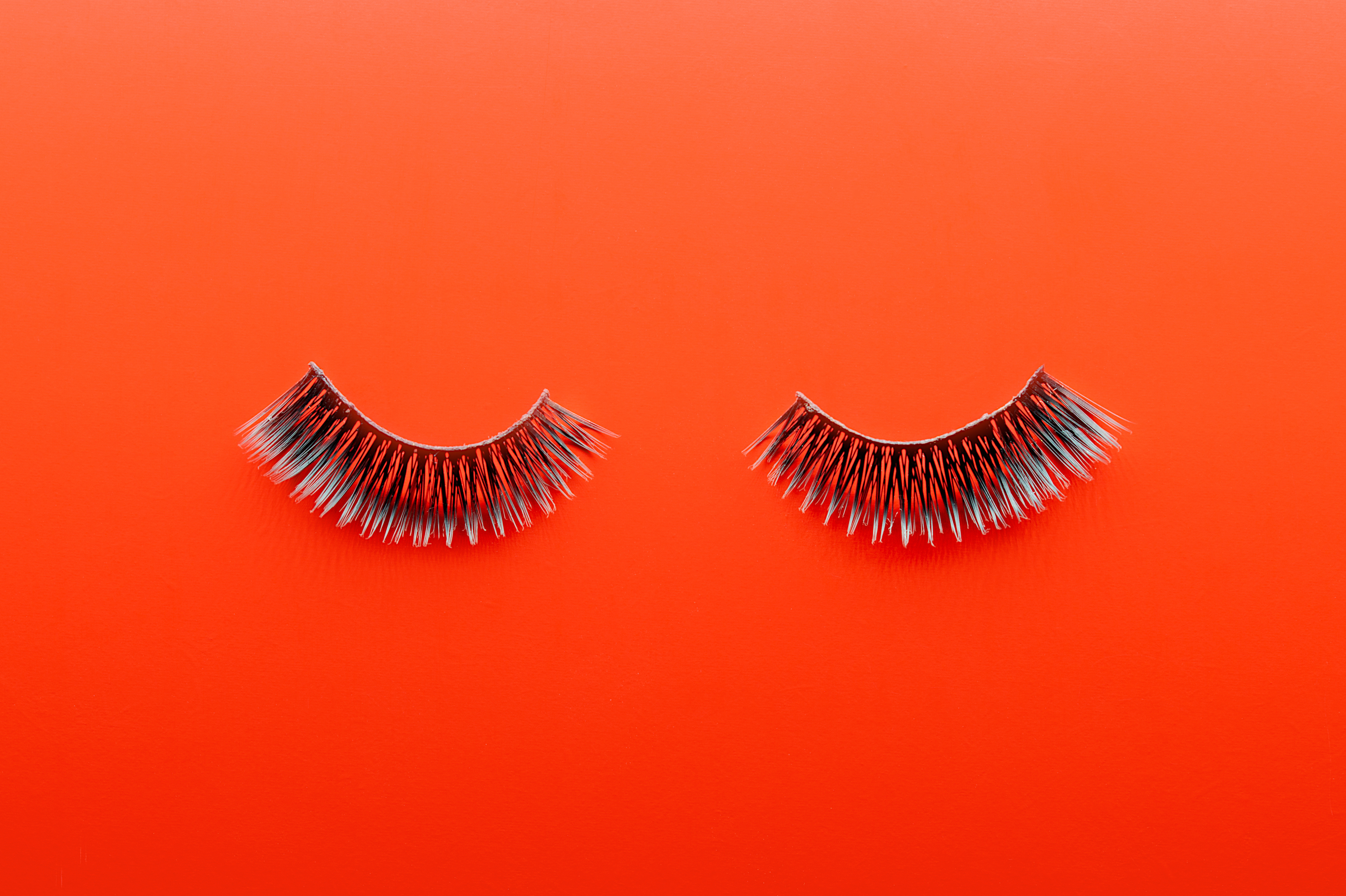 A stock photo of false eyelashes on an orange background