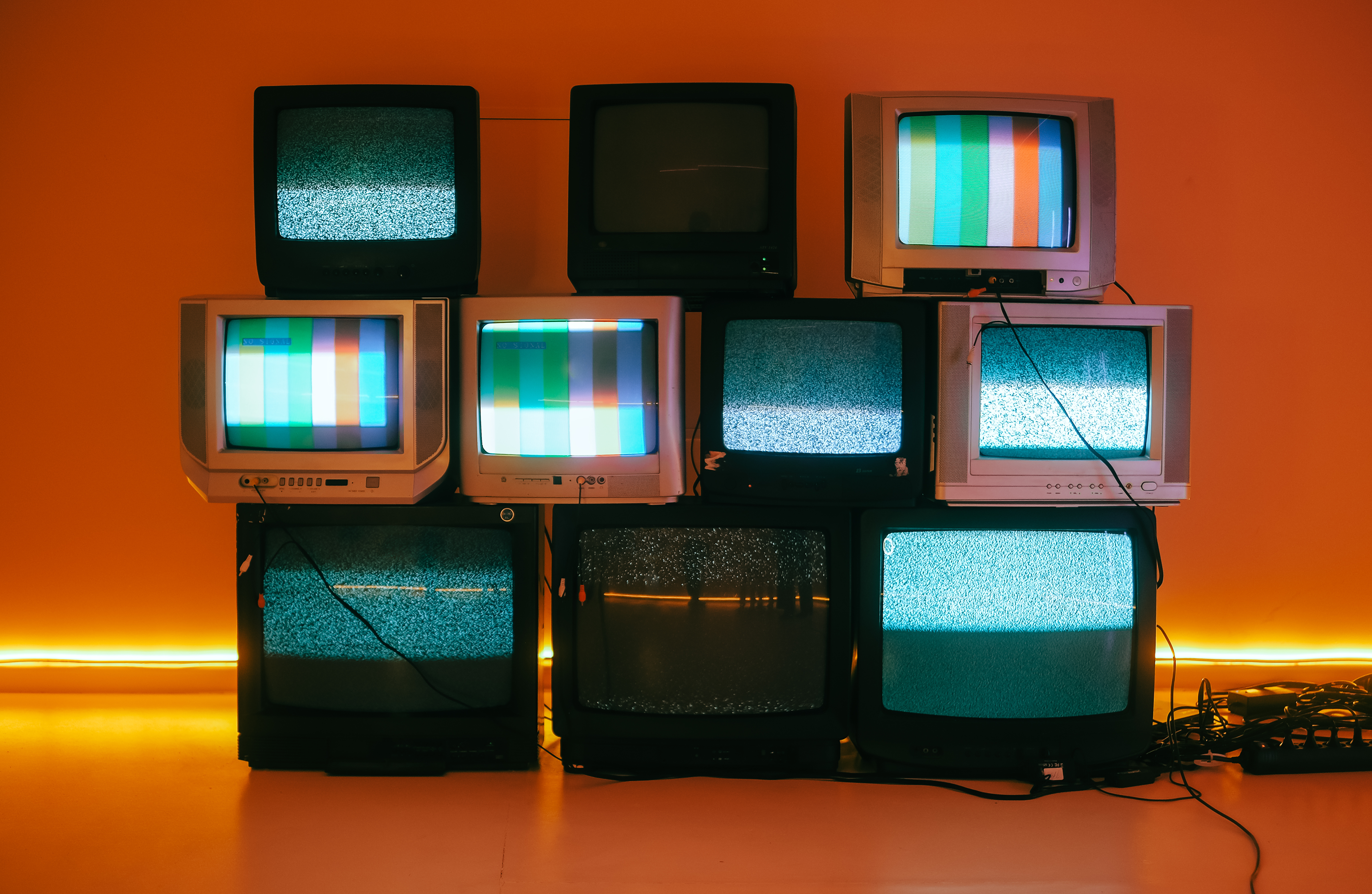 A display of TVs against an orange background. 