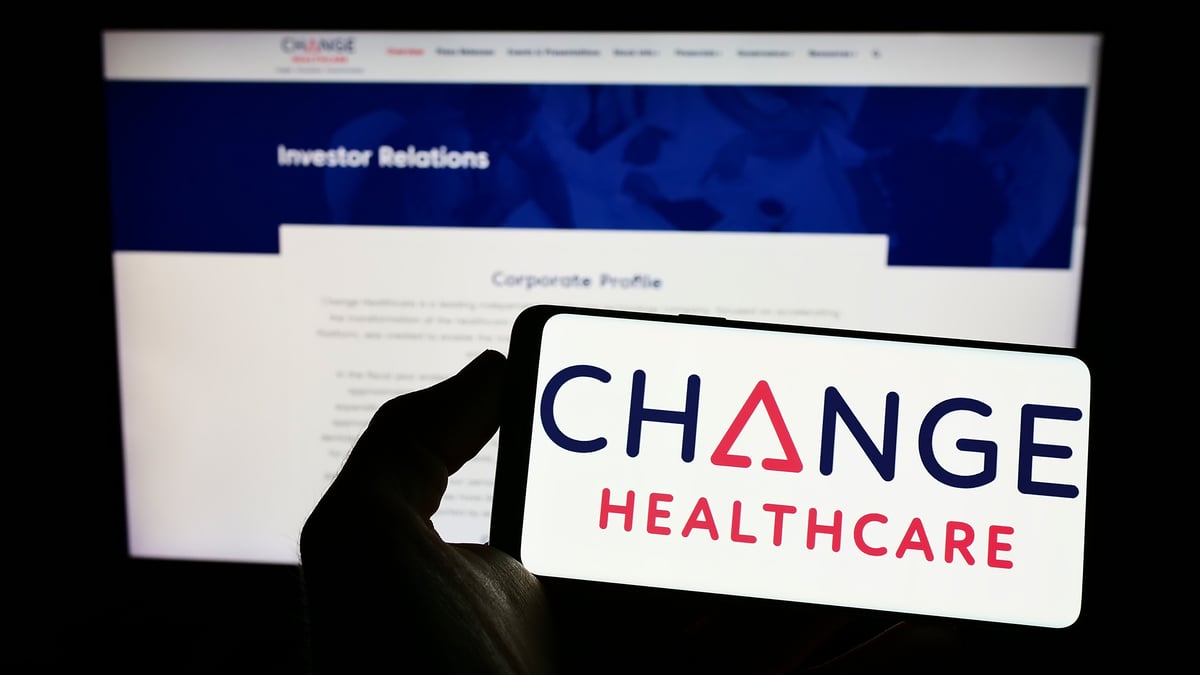 A phone screen displays Change Healthcare's logo in front of a laptop screen that shows the company's website