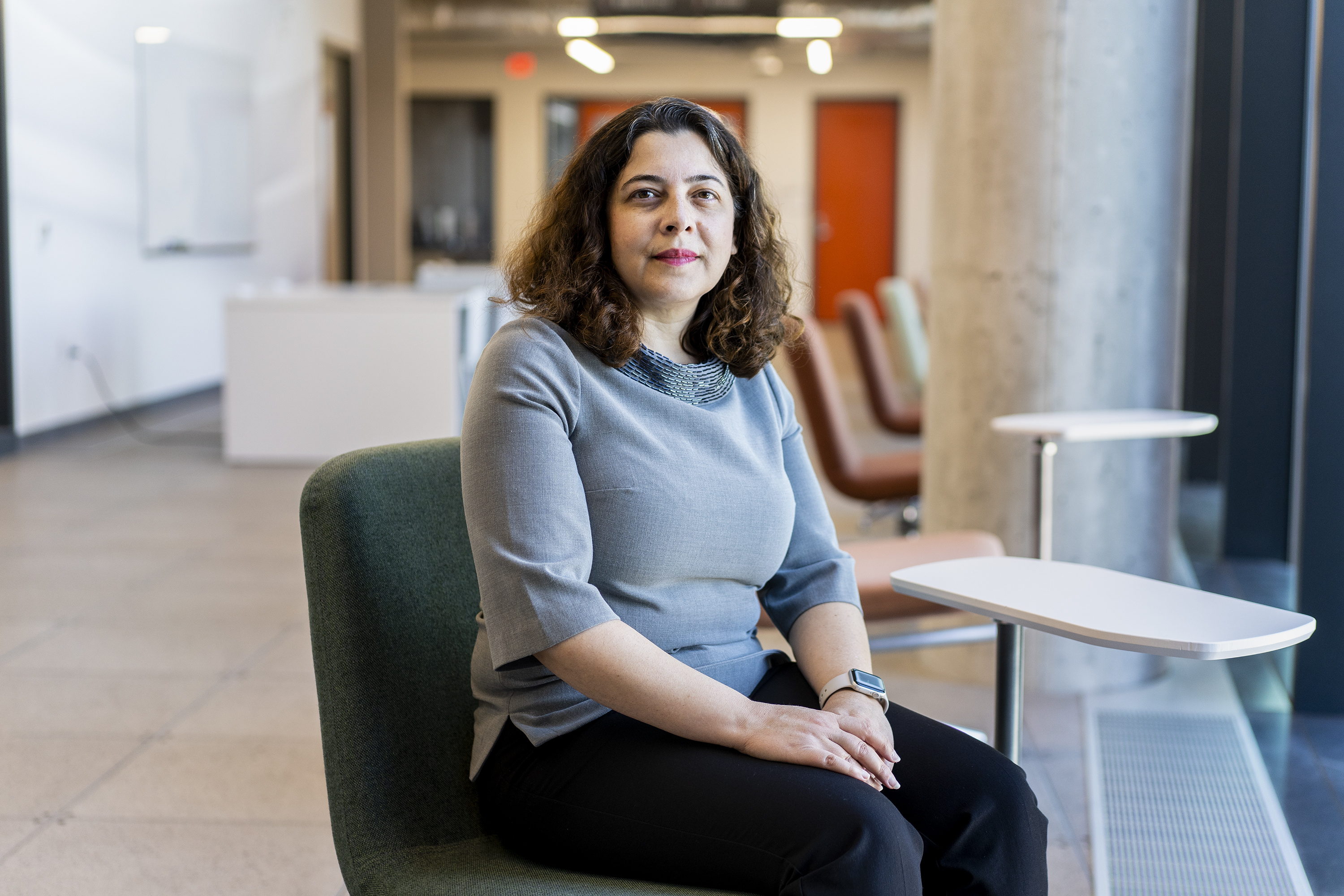 Dr. Nicole Hashemi poses for a portrait, sitting near a window with her hands crossed on her lap.