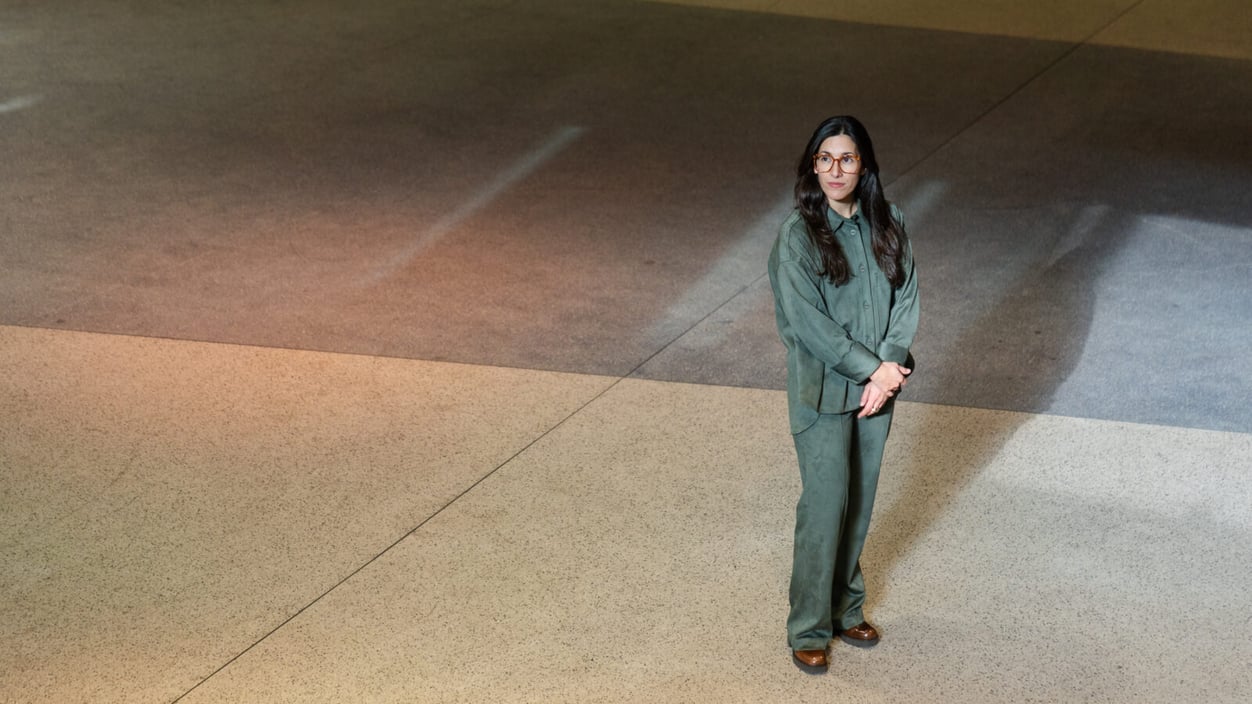A woman with long hair and glasses stands looking up