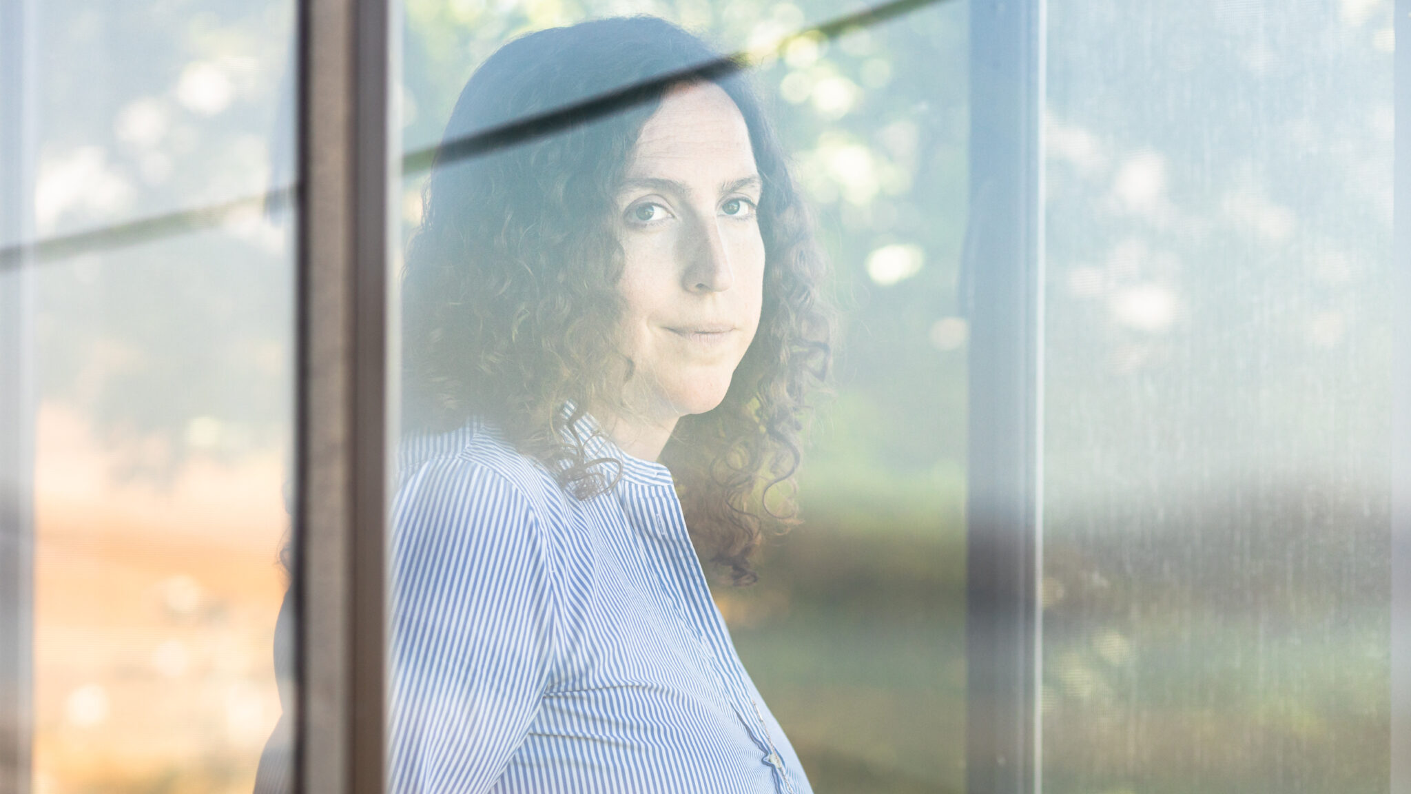 Jean Swidler looks out the window at her home.