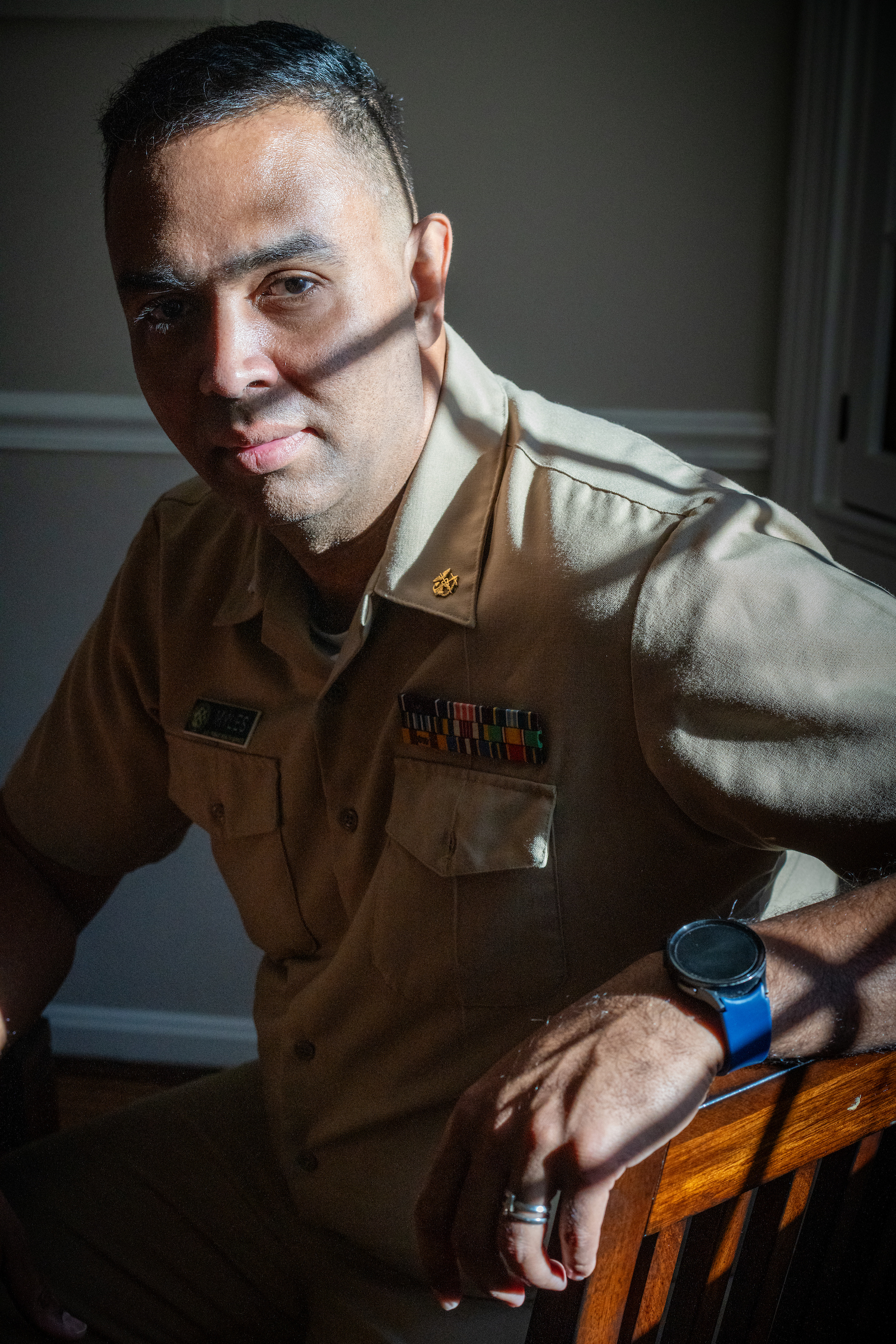 A man stares solemnly at the camera in his uniform from the Public Health Service. Shadows cross over his face. 