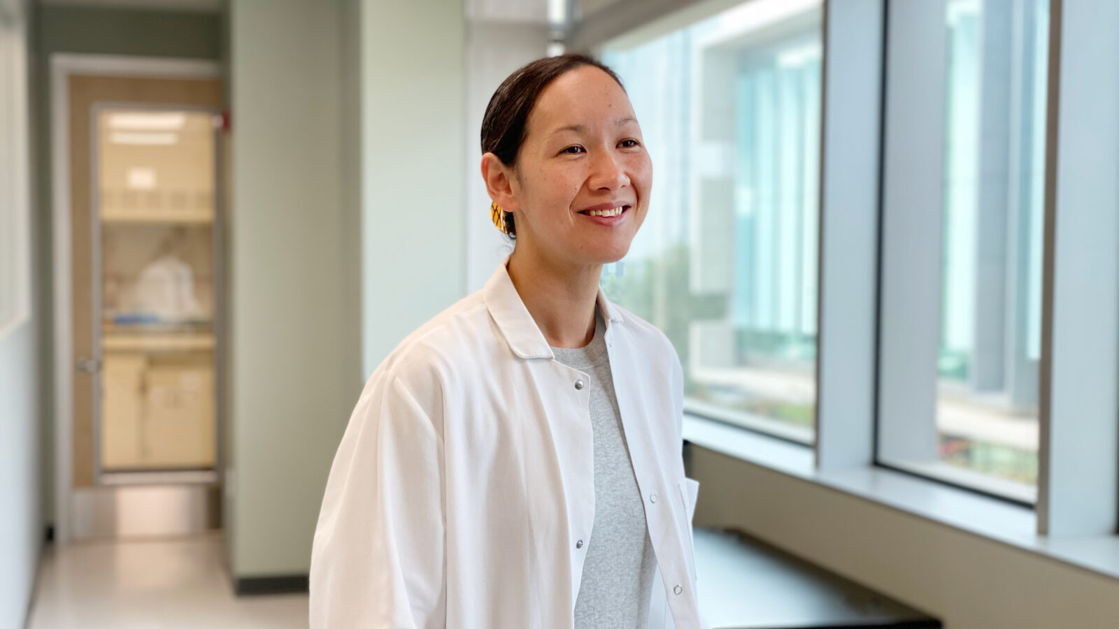 Sydney Ramirez stands smiling in a white coat.